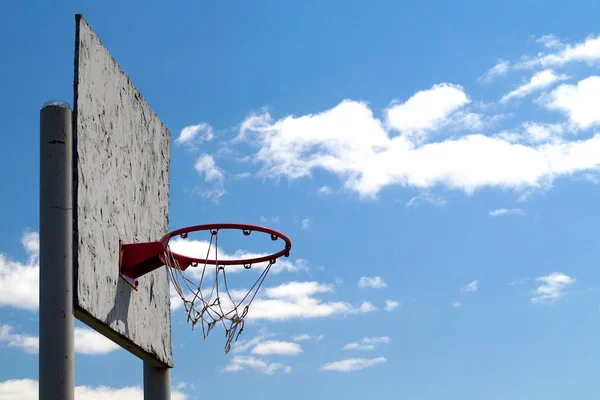 Beyaz bulutlar ile mavi gökyüzüne karşı streetball için kırmızı basketbol potası. Spor ekipmanları.