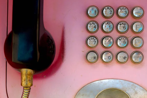 Metal düğmeli eski soluk kırmızı telefon. Kentsel iletişim teknolojileri.