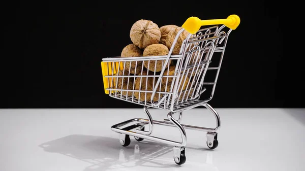 Concept shopping cart with walnuts on white background, diet food. — Stock Photo, Image