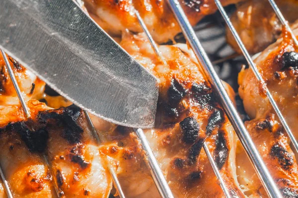 knife pierces the meat on the grill