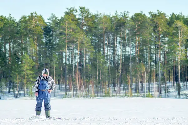 Fisherman catches fish in the winter on the background of the winter forest — Stock Photo, Image