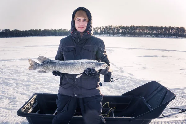 Young man holding fish catch a big pike ice fishing — Stock Photo, Image