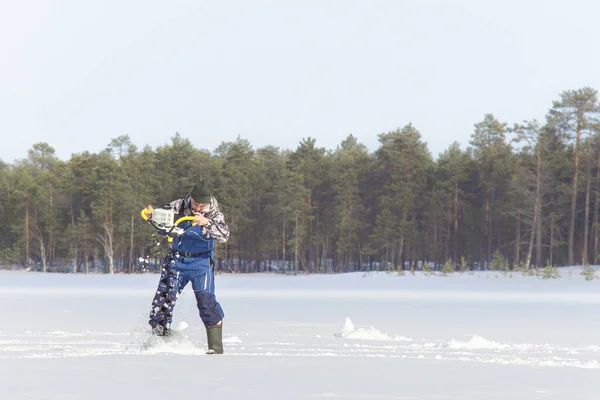 A man on a winter fishing drill hole ice drill — Stock Photo, Image