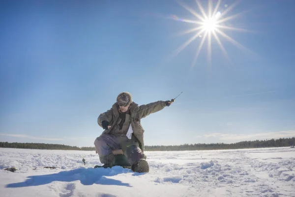 Pescador pesca invierno pesca en un día soleado brillante — Foto de Stock