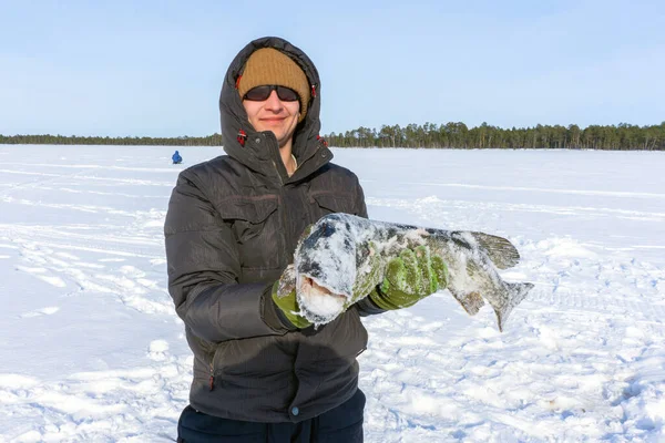 Young man holding fish catch a big pike ice fishing — Stock Photo, Image