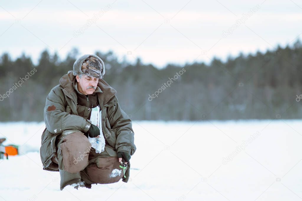 man catches a fish in the winter