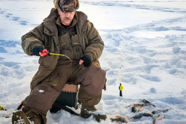 男は氷の穴から釣りをしている冬の釣り. — ストック写真