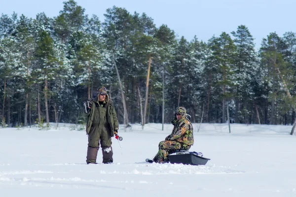 冬の森を背景にした冬の湖釣りの漁師たち。冬の冬のスポーツ冬の釣り — ストック写真