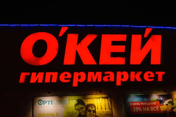 Tyumen, Rusia - 03 de octubre de 2019: Letrero del nombre doblado de grandes letras rojas por encima de la entrada al hipermercado de la tienda Ok. Fotografía nocturna — Foto de Stock
