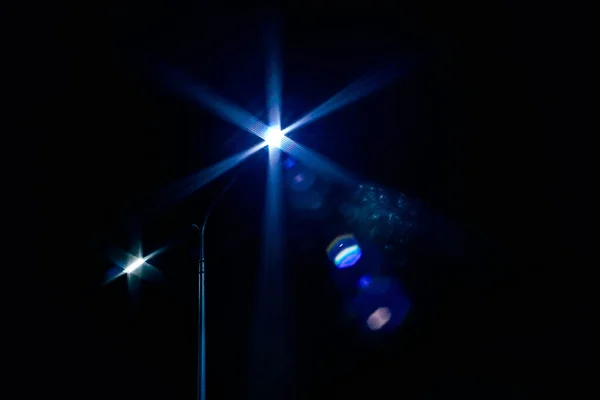 Licht einer Laterne auf schwarzem Hintergrund in der Nacht. die Abstraktion der Straßenlaterne. Laternenmasten am Straßenrand. Blaues Licht leuchtet — Stockfoto