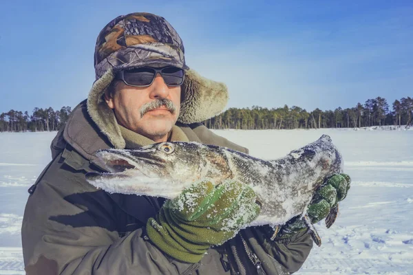 Man winter is holding a fish pike closeup of winter fishing. winter sports Hobbies — Stock Photo, Image