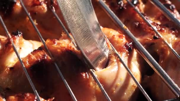 Pierces a fried chicken with a knife checking the readiness of the meat on the grill close up — Stock Video