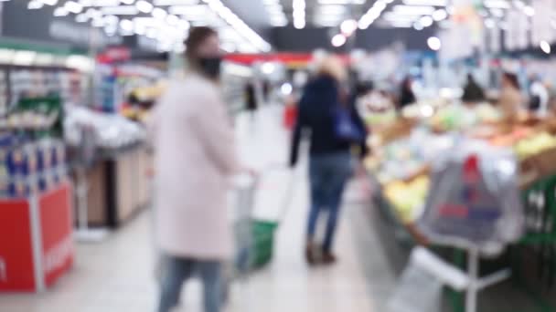 Suddig bakgrund av en livsmedelsbutik, människor går i masker coronavirus — Stockvideo