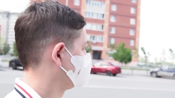 Homem andando com mochila e vestindo uma máscara de poluição facial para se proteger do coronavírus . — Vídeo de Stock