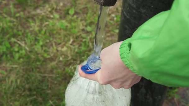 Verzamelt het water van de ouderwetse waterpomp. Hij giet het in een fles. — Stockvideo
