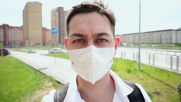 リュックを背負った男は顔の汚染マスクをしてコロナウイルスから身を守る. — ストック動画