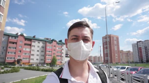 Молодой человек в защитной медицинской маске ходит по городу. Карантин, коронавирус — стоковое видео