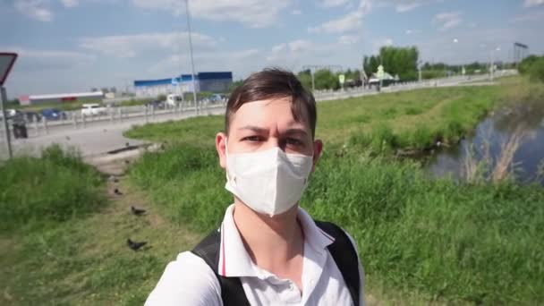 Selfie jovem usando uma máscara facial médica para proteger contra a pandemia de Coronavirus. Homem na natureza COVID-19 ao ar livre — Vídeo de Stock