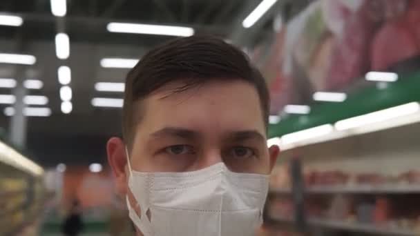 Портрет молодого человека в медицинской маске, идущего в супермаркет. Парень идет в магазин в защитной маске от вируса. Понятие здоровья. COVID-19 — стоковое видео