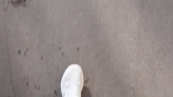 Een man met witte sneakers loopt op een zonnige dag door de straat. gezichtspunt video, eerste persoon — Stockvideo