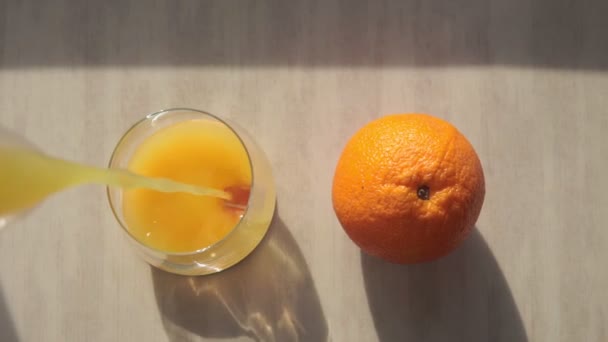 Chorro de jugo de naranja exprimido vertiendo, disparar de cerca con enfoque selectivo. Contiene bokeh en el fondo para el espacio de copia — Vídeos de Stock