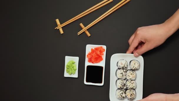 Rouleau de sushi japonais, gingembre, sauce soja, fond noir rustique, espace de copie — Video