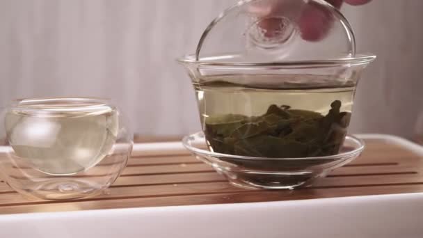 Té verde chino de una tetera de vidrio en una pequeña taza — Vídeo de stock