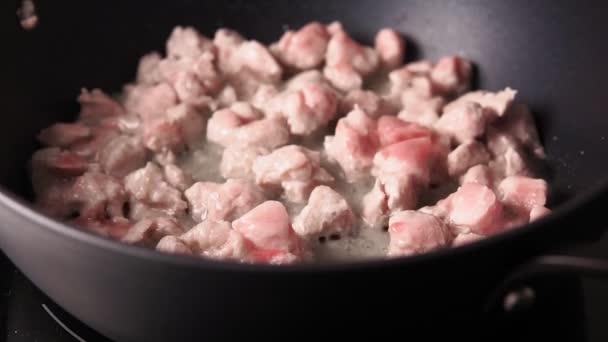 Cocinar trozos de carne frita de cerdo en una sartén, en aceite de oliva, enfoque selectivo de primer plano — Vídeo de stock