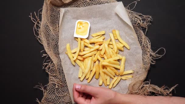 Patatine fritte in una carta bianca con salsa di formaggio sfondo nero. vista dall'alto, mangiare cibo spazzatura — Video Stock