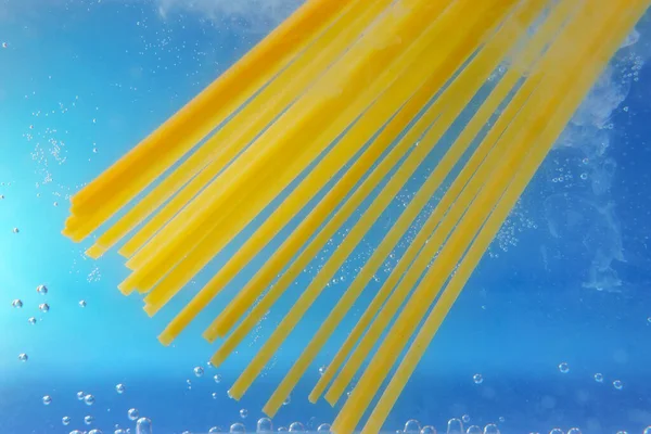 Throwing pasta pappardelle into boiled water in, close-up. selective focus, cooking pasta