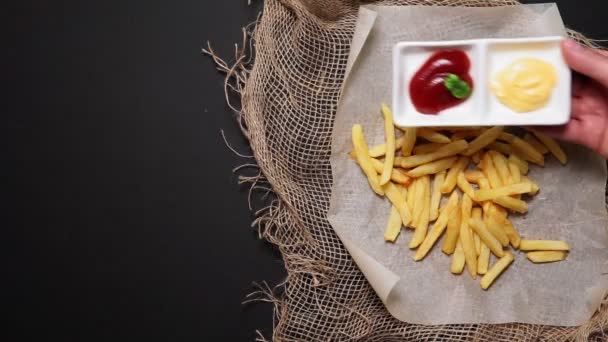 Servieren Käsesauce und Ketchup zu Pommes frites ungesundes Essen, Draufsicht, auf schwarzem Hintergrund. flache Lage. — Stockvideo