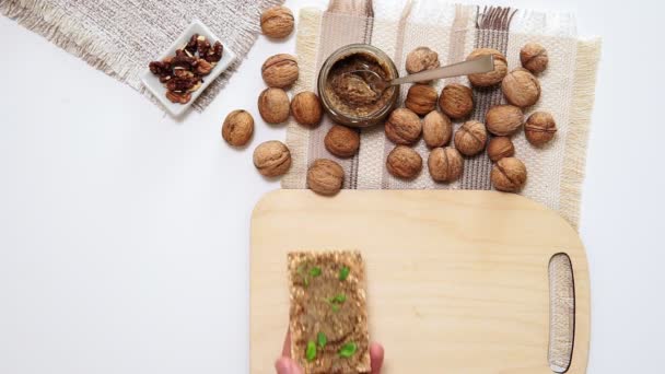 Nueces y mantequilla de nuez en el pan bocadillos saludables vista superior. plano laico — Vídeos de Stock