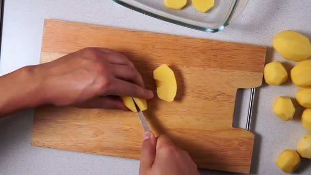 Hombres manos rebanar patatas crudas con un cuchillo de cocina en una tabla. Vista superior — Vídeo de stock