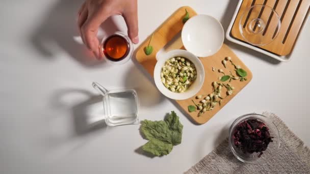 Čínská čajová párty. Sušené granule různých druhů čaje. Flatlay, pohled shora. bylinkový čaj, na bílém pozadí — Stock video