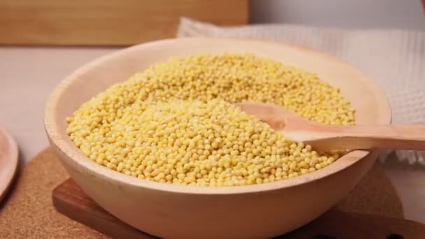 Millet in a wooden bowl standing on the kitchen. pours dry millet selective focus — Stock Video
