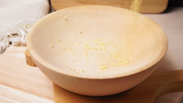 Millet in a wooden bowl standing on the kitchen. pours dry millet selective focus — Stock Video