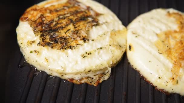 Gegrilde haloumi kaas wordt gegrild op een donkere metalen grill pan in close-up - up. — Stockvideo