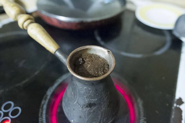 Кофе варится в медной тюрке на плите Лицензионные Стоковые Фото
