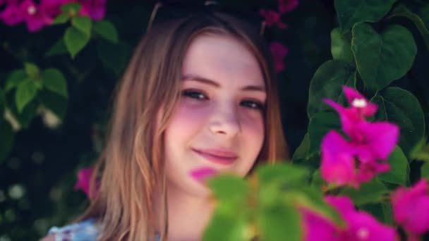 Hezká dívka portrét poblíž rozkvetla strom v parku. Koncepce mládeže a přírodních krás. Žena a jarní příroda, přírodní kosmetika — Stock video
