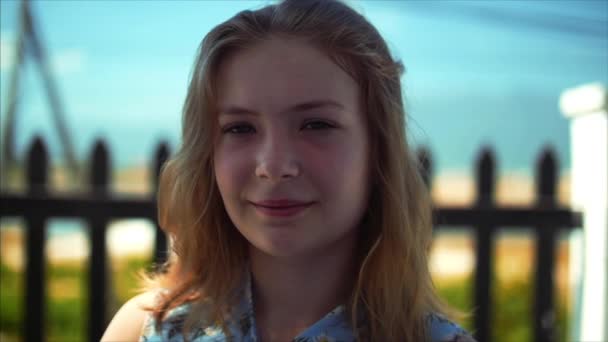 Close up portrait of European beautiful cute blonde young woman or cheerful girl smiling looking at camera, running hand through hair blowing in wind, slow motion. — Stock Video