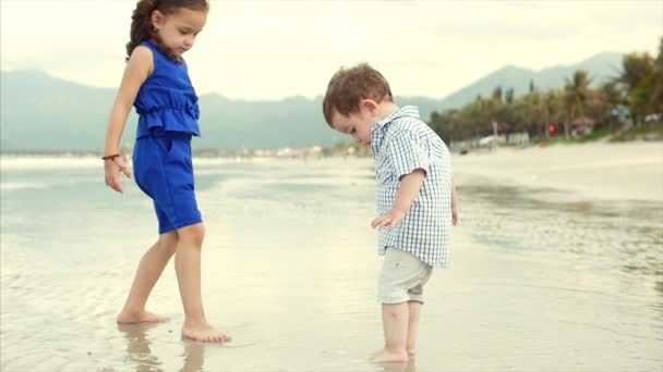 Genç aile, çocuk, kardeşi ve kız kardeşi okyanus sahil oynamak. Mutlu aile, sahil yürüyüş. — Stok video