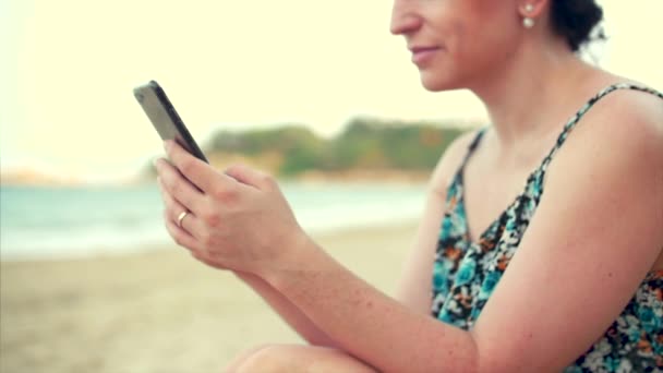 Молодая счастливая белая женщина с помощью смартфона у моря . — стоковое видео
