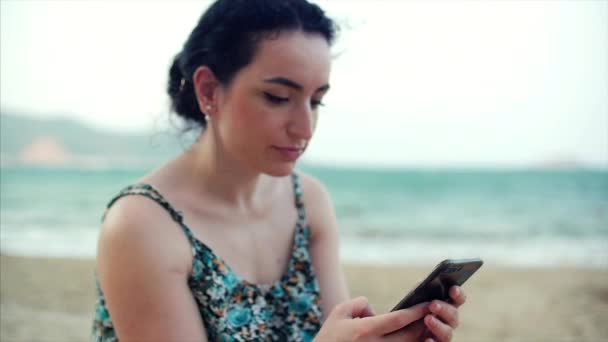 Deniz kenarında Smartphone kullanan genç mutlu beyaz kadın. — Stok video