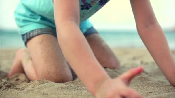 Маленька дівчинка на пляжі, щаслива маленька дитина грає з піском на пляжі. Дитина, дитина, діти, емоції . — стокове відео