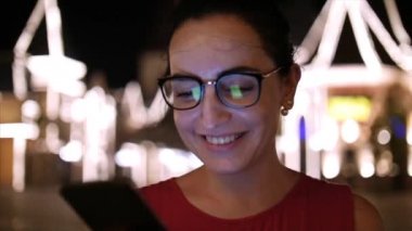 Bir gece şehirde arka plan gece şehrin sokaklarında yürürken bir cep telefonu kullanarak çekici kadın. Stok görüntüleri.