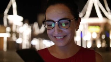 Çekici kız bir gece şehirde arka plan gece şehrin sokaklarında yürürken bir cep telefonu kullanarak. Stok görüntüleri.