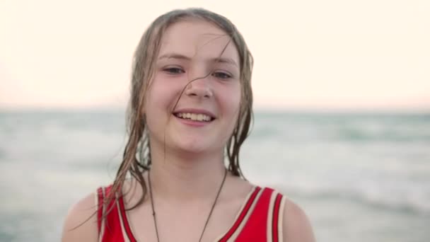 Zbliżenie, portret pięknej młodej dziewczyny nastoletnie patrząc na kamery, uśmiechnięty, tropikalnej plaży zwolnionym tempie. Stockowy. — Wideo stockowe
