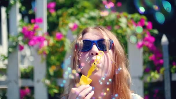 Heureuse adolescente souriante apparence caucasienne, souriante regardant la caméra, soufflant des bulles de savon en été à l'extérieur. Gros plan. Images de stock . — Video