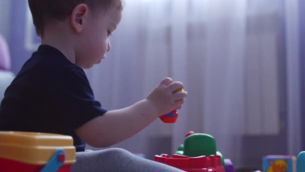 Мальчик играет с машинами в игрушечном гараже. Запись. 4K — стоковое видео