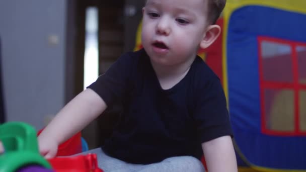 Kleine jongen spelen met auto's in speelgoed garage. Beeldmateriaal. 4k — Stockvideo